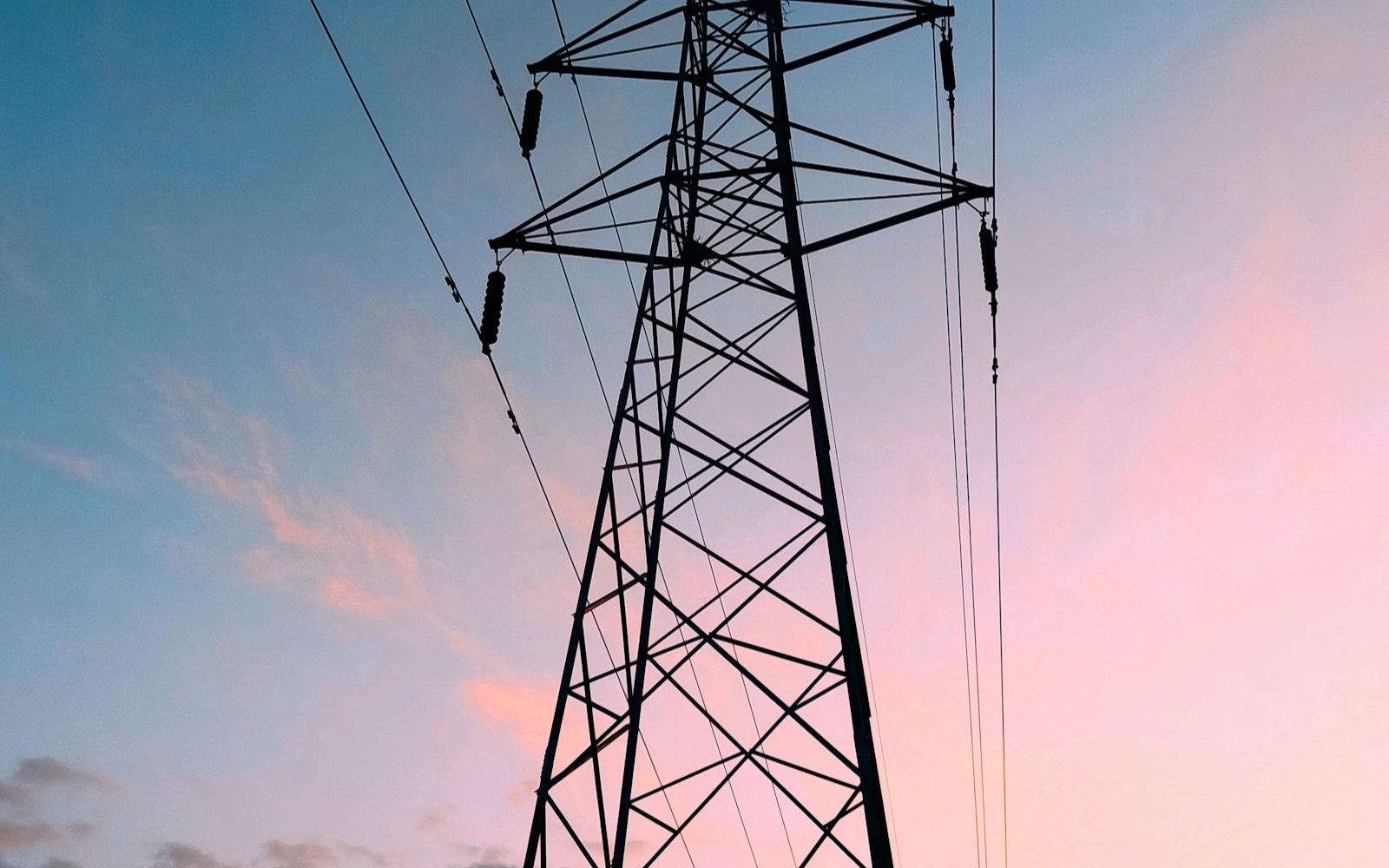 High-voltage transmission tower silhouetted against a sunset sky