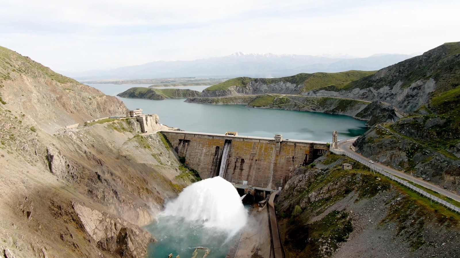 Aerial view of a hydroelectric dam releasing water into a turquoise reservoir